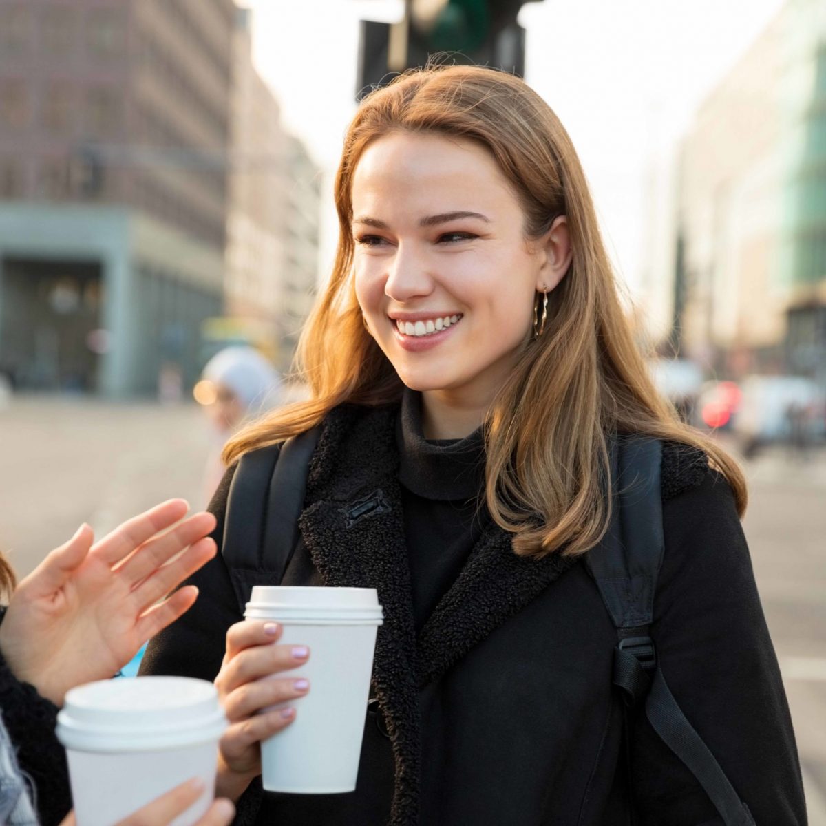 Woman friends having coffee and talking on the city street
